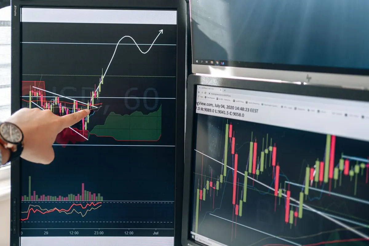 Trader analyzing gold price charts on multiple monitors